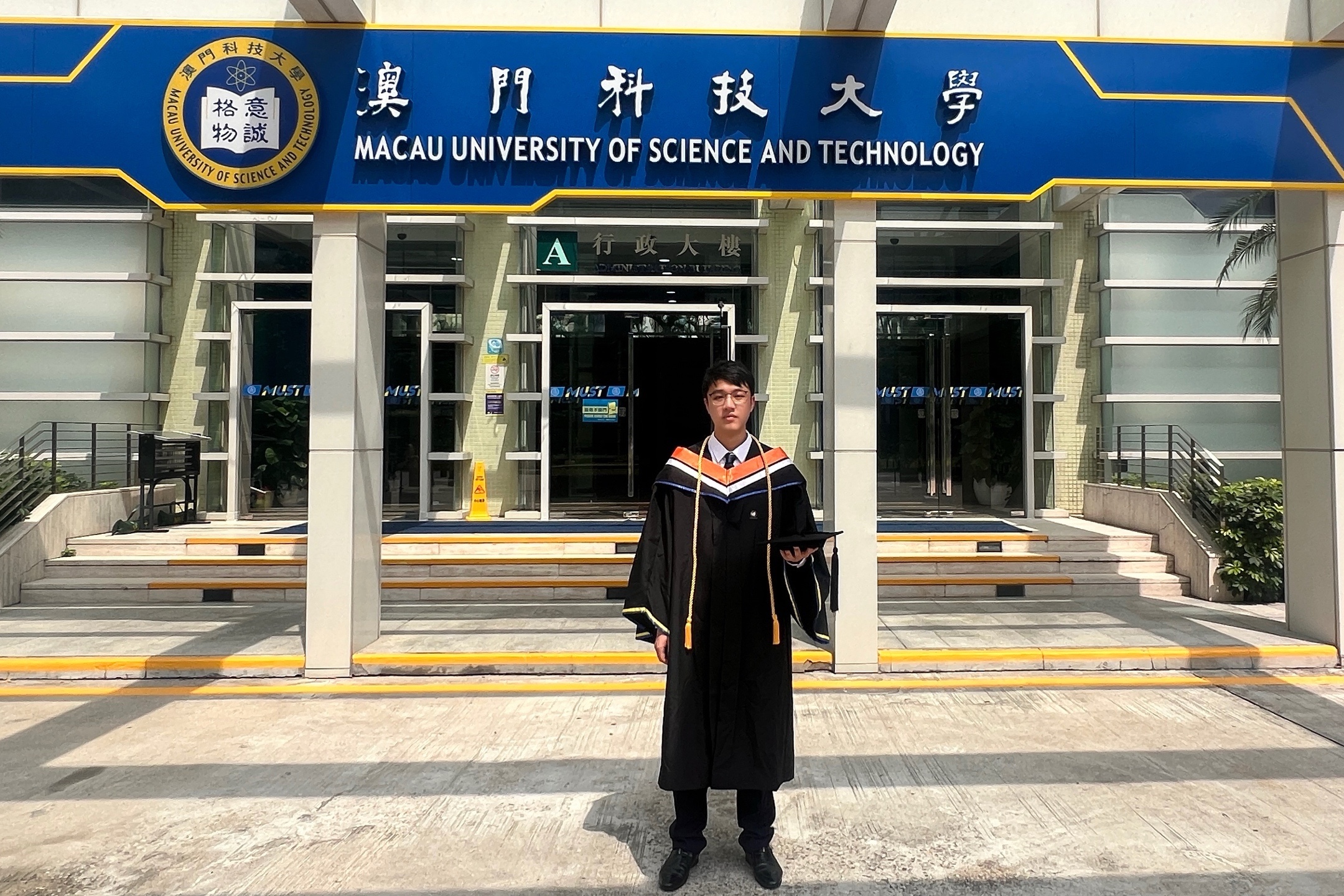 Boyi Fu in graduation attire on the M.U.S.T. campus